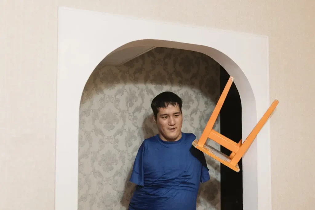 Серик Отынчинов переносил табурет на кухню и остановился, чтобы поговорить с двумя друзьями из интерната, с которыми он арендует квартиру в Омске, январь 2022. Фото: Вадим Брайдов.