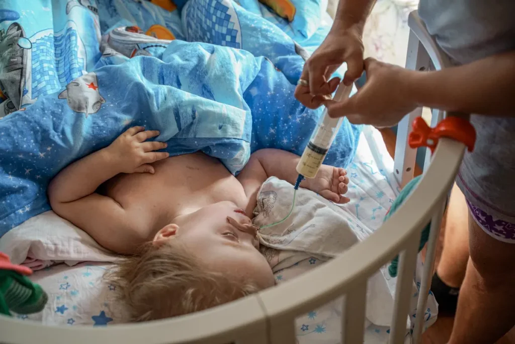 Мама Оксана Чукавина встаёт в полшестого утра и даёт дочке Полине с паллиативным диагнозом лекарства. Семья получает пособие по инвалидности, но специальное питание выходит дороже. Центр «Вместе» приобрели для семьи уголь и дрова на зиму, чтобы дети не оказались в учреждении. Фото: Дмитрий Яцюк.