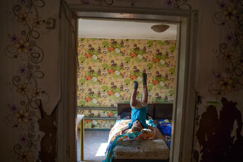 Артём Чукавин кувыркается на своей кровати, село Мочище, Новосибирская область. У него есть пять братьев и сестёр. Центр поддержки семей и детей «Вместе» закупил для Чукавиных дрова и уголь на зиму, чтобы дети не оказались в приюте. Фото: Дмитрий Яцюк.