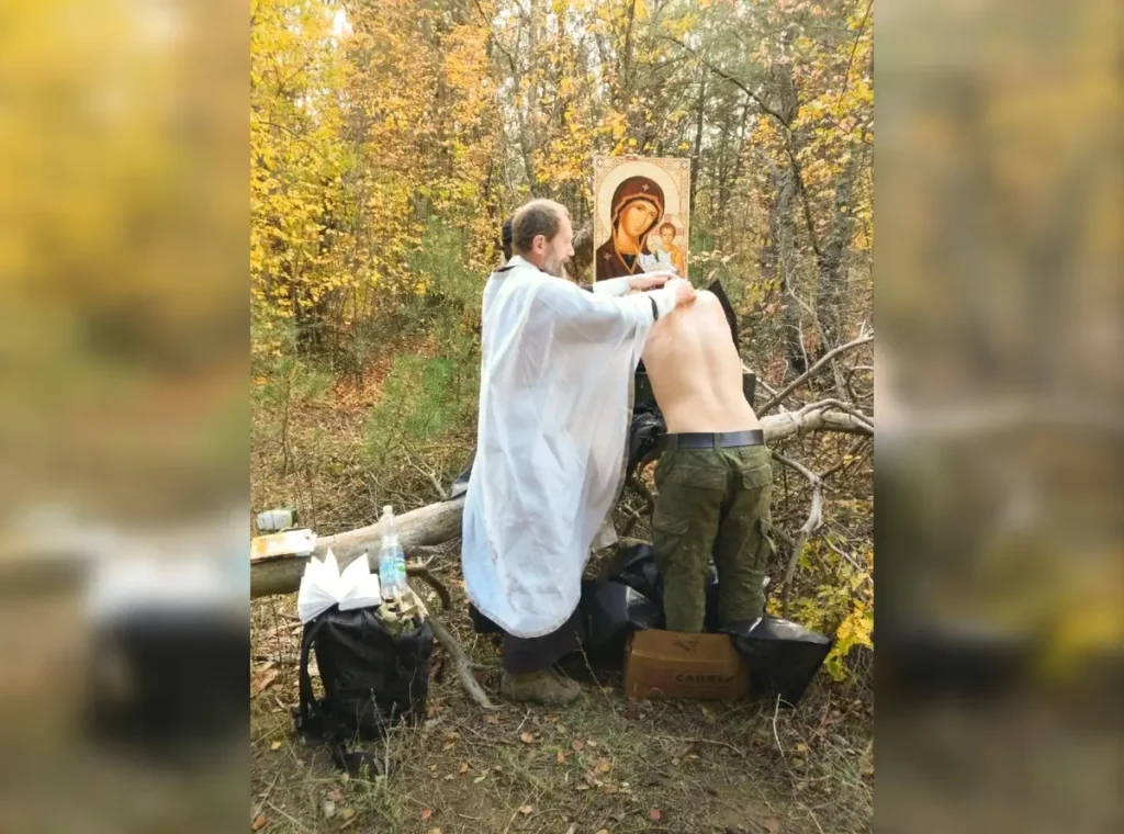Уфимский священник Виктор Иванов крестит военнослужащего осенью 2022 года в черных пакетах, предназначенных для трупов. Источник: канал "«Позывной Бекас» в Telegram.