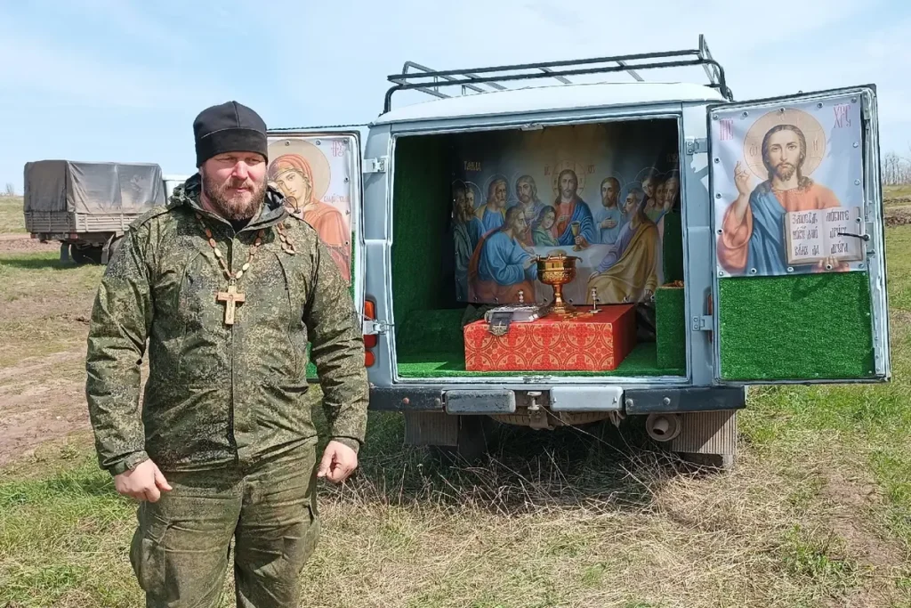 Священник Роман Чебоненко стоит рядом с полевым «храмом-буханкой». Фото вместе с постом выложено 6 октября 2023 года, в котором священник благодарит за закрытие денежного сбора на покупку нового УАЗа для полевого храма. Источник: личная страница Чебоненко в ВКонтакте.