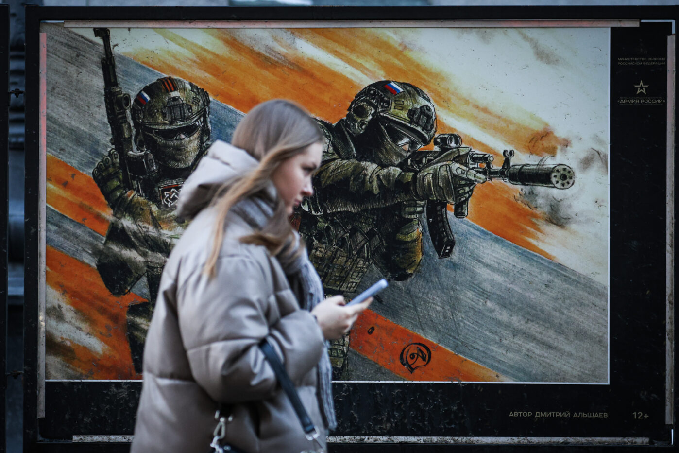 Девушка проходит мимо плаката с изображением российских военнослужащих на уличной выставке в Санкт-Петербурге